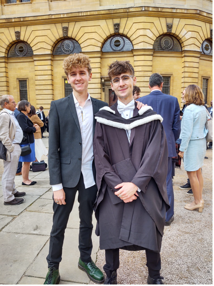 Phillip Olney smiling to the camera with a friend during graduation